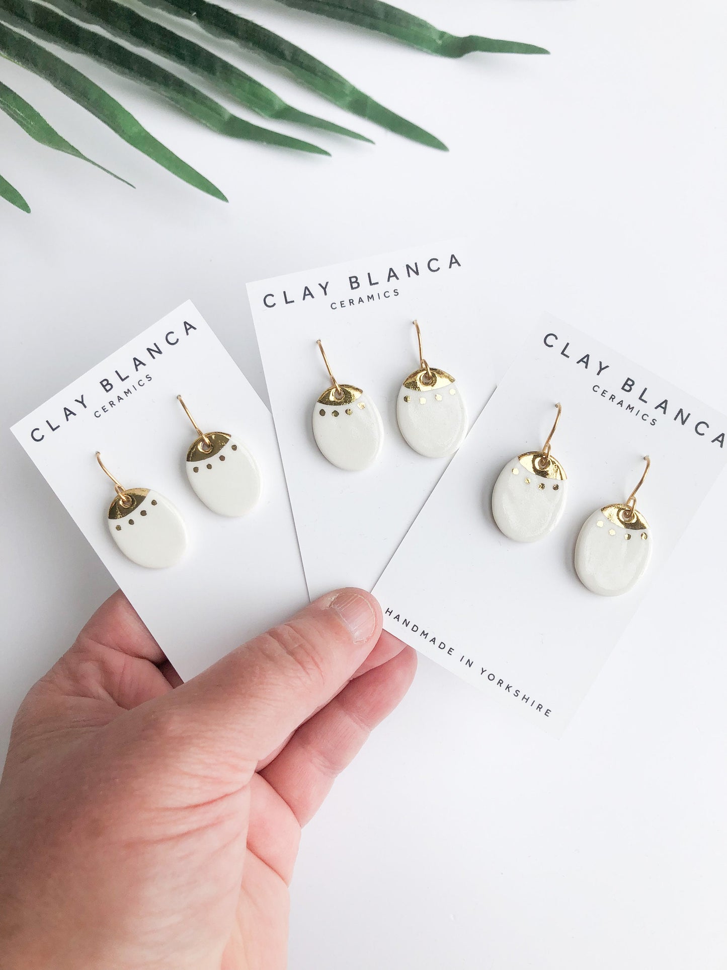 White oval dangles with gold detail
