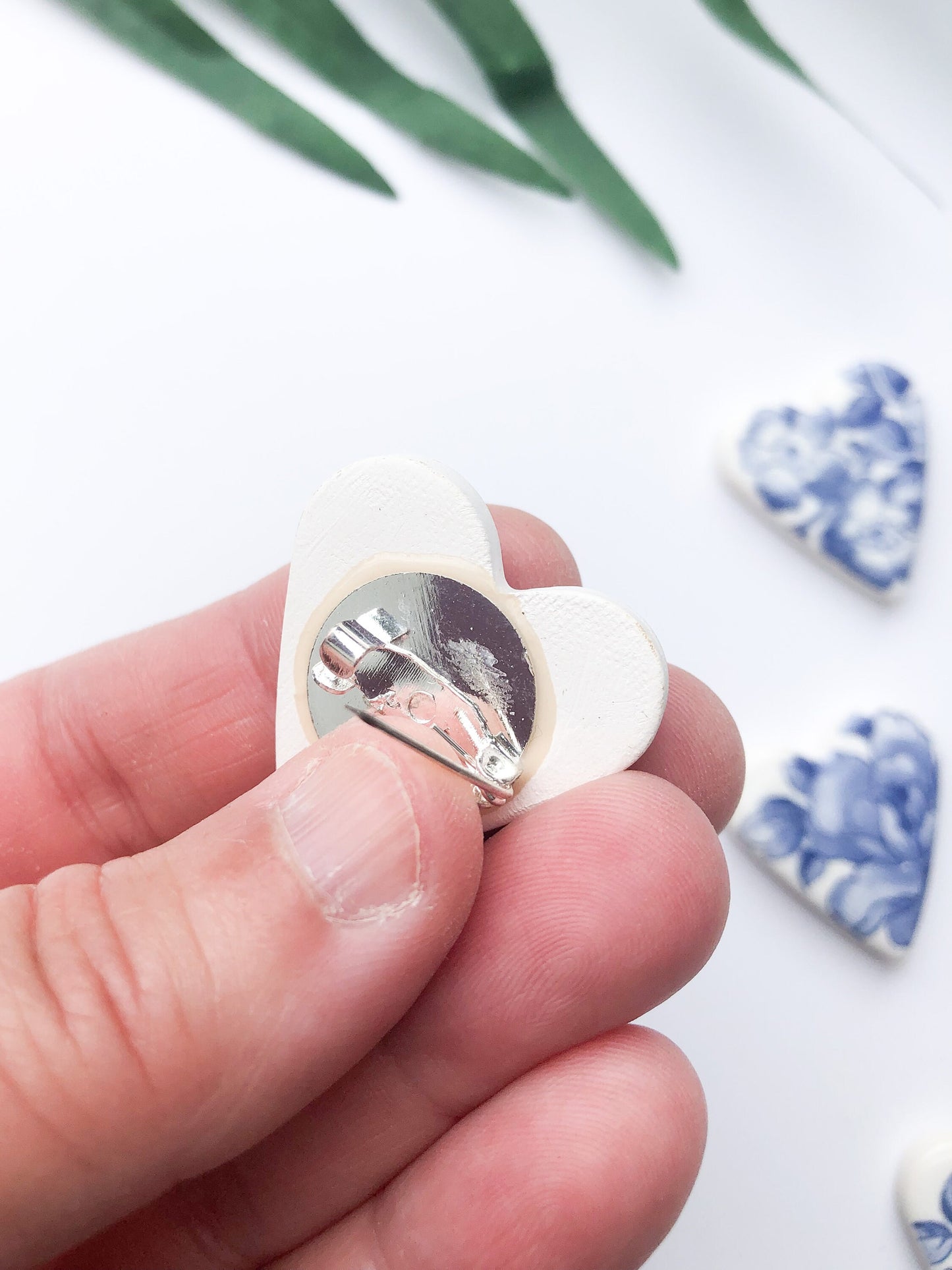 White clay heart brooch with blue floral design