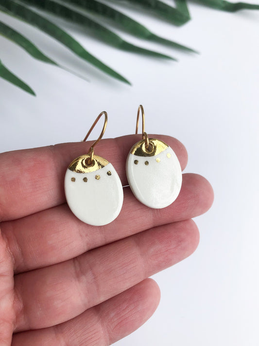 White oval dangles with gold detail