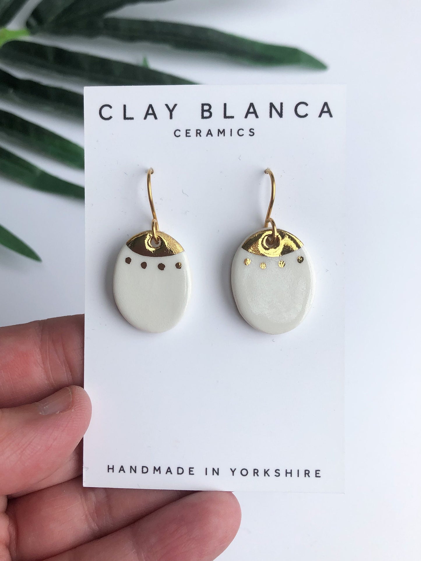 White oval dangles with gold detail